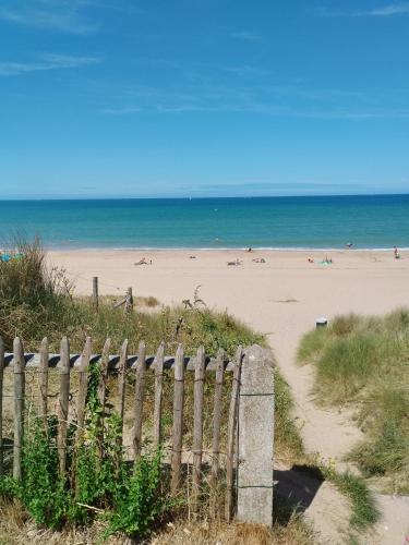 - une plage avec une clôture en bois et l'océan dans l'établissement Cocooning varaville, à Varaville