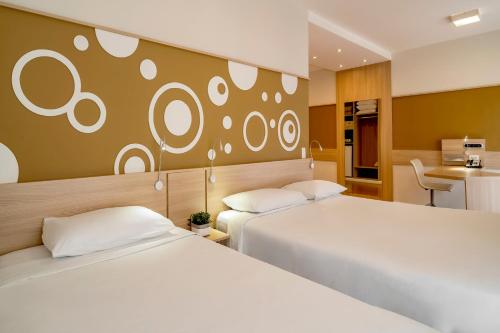 a hotel room with two beds and a desk at Mercure Sao Paulo Alamedas in Sao Paulo