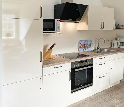 a white kitchen with white cabinets and a microwave at Landhaus am Sonnenberg in Bad Bertrich