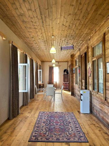 a living room with a wooden ceiling and a rug at Villa Obcha - Whispering Vines Guesthouse in Bagdatʼi