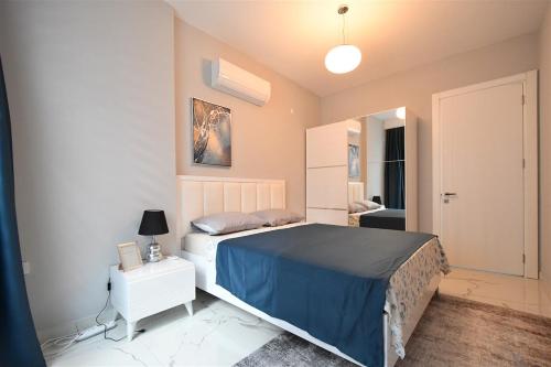 a bedroom with a large bed with a blue blanket at 0017 White Sail Cozy 1-Bedroom Apartment Steps from Yekta Mall in Mahmutlar, Alanya in Alanya