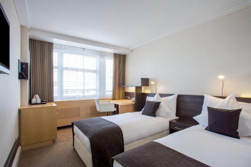 a hotel room with two beds and a desk at Crowne Plaza Zürich by IHG in Zürich