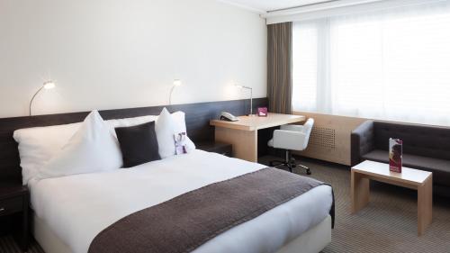 a hotel room with a bed and a desk at Crowne Plaza Zürich by IHG in Zürich