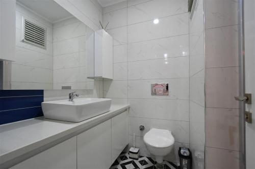 a white bathroom with a sink and a toilet at 0017 White Sail Cozy 1-Bedroom Apartment Steps from Yekta Mall in Mahmutlar, Alanya in Alanya