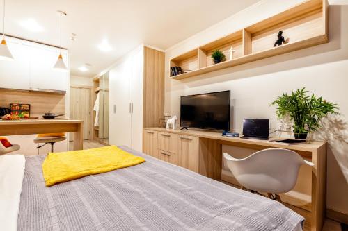 a bedroom with a bed and a desk with a television at Y'estoria апарт-отель, район EXPO центра in Astana
