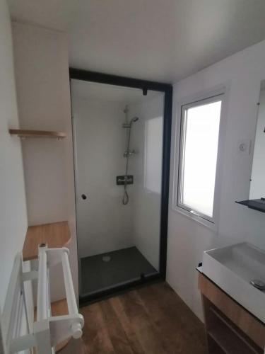 La salle de bains est pourvue d'une douche, d'une fenêtre et d'un tabouret. dans l'établissement Mobil-home bord de plage à Saint-Hilaire-de-Riez, à Saint-Hilaire-de-Riez