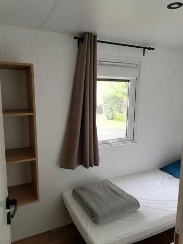 un lit dans une chambre avec une fenêtre dans l'établissement Mobil-home bord de plage à Saint-Hilaire-de-Riez, à Saint-Hilaire-de-Riez
