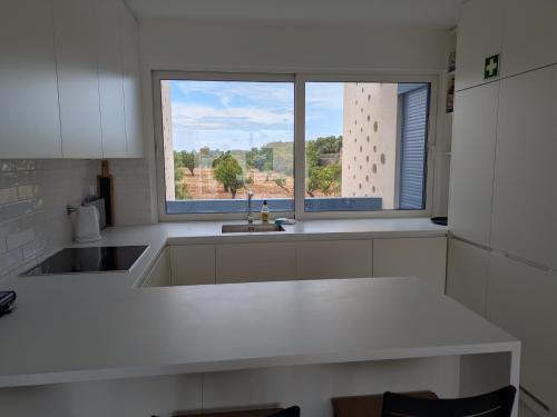 een keuken met een wit aanrecht en een raam bij Casa do Forte by Wave Algarve in Cabanas de Tavira