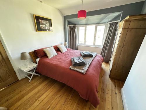a bedroom with a large bed with a red blanket at Oxford's cosiest 3 bedroom home with off street car parking in Oxford