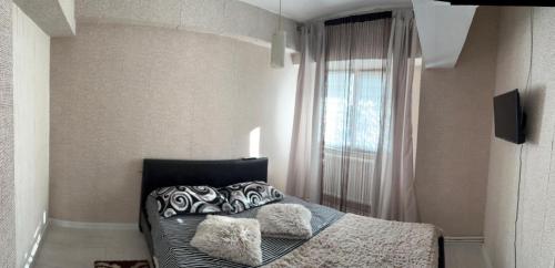 a bedroom with a bed with pillows and a window at Alfredo Apartament in Buzau