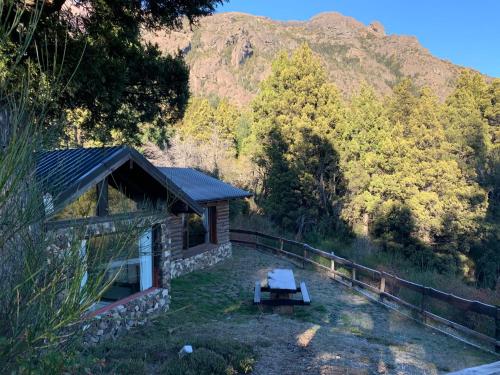 a cabin with a picnic table in front of a mountain at Estancia Del Carmen Mountain Resort in San Carlos de Bariloche