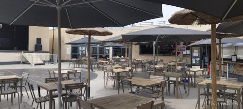 an empty restaurant with tables and chairs with umbrellas at Camping LES DUNES Mobil home 6 personnes in Torreilles