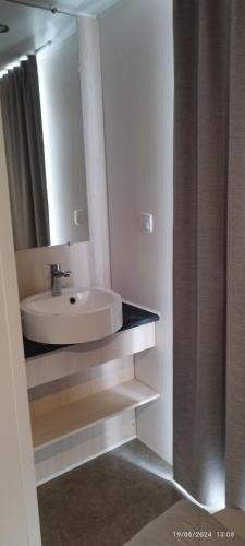 une salle de bain avec un lavabo et un miroir dans l'établissement Camping LES DUNES Mobil home 6 personnes, à Torreilles