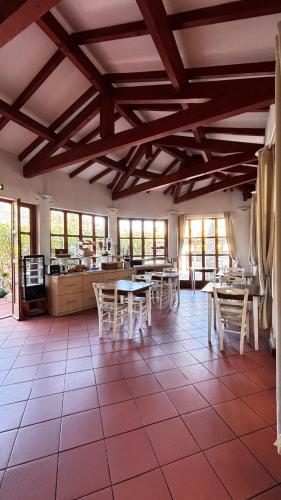 une grande pièce avec des tables, des chaises et des fenêtres dans l'établissement Hotel La Bastide, au Lavandou