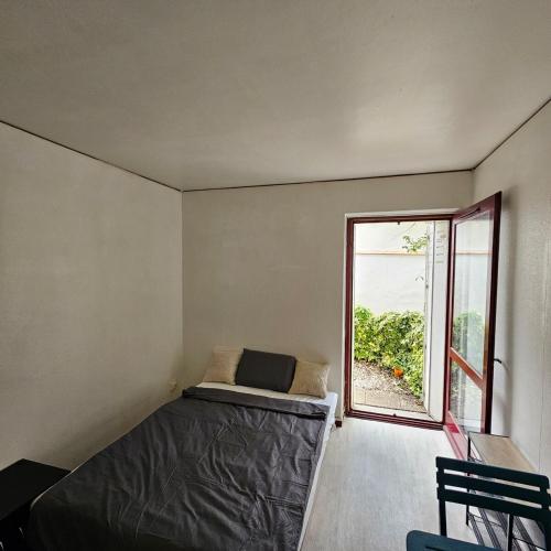 une chambre avec un lit et une grande fenêtre dans l'établissement Studio calme avec petit jardinet, à Bordeaux