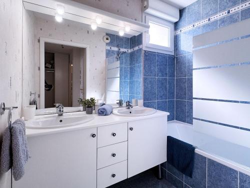 une salle de bain carrelée bleue avec deux lavabos et une baignoire dans l'établissement Joli 3P avec terrasse et Garage proche Centre, à Strasbourg