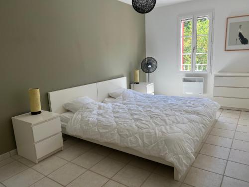 une chambre blanche avec un lit et une fenêtre dans l'établissement Les Marrouges de Saint Jean, à Collobrières