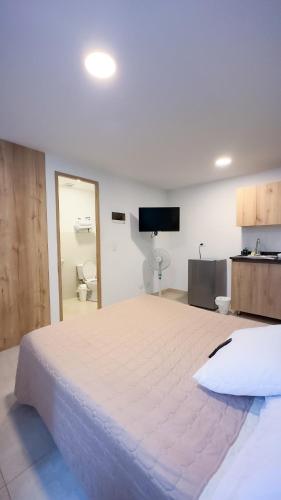 a large white bed in a room with a tv at Edificio Fenicia Lofts Laureles in Medellín