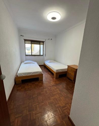 a room with two beds and a window at Costa Caparica Beautiful in Costa da Caparica