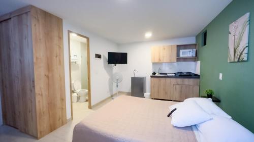 a bedroom with a large bed and a kitchen at Edificio Fenicia Lofts Laureles in Medellín