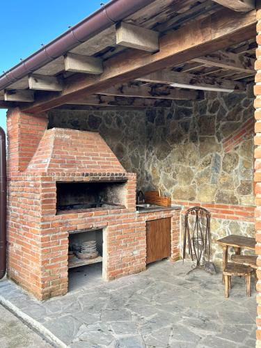 an outdoor brick oven with a table and a chair at Villa Obcha - Whispering Vines Guesthouse in Bagdatʼi