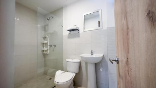 a white bathroom with a toilet and a sink at Edificio Fenicia Lofts Laureles in Medellín