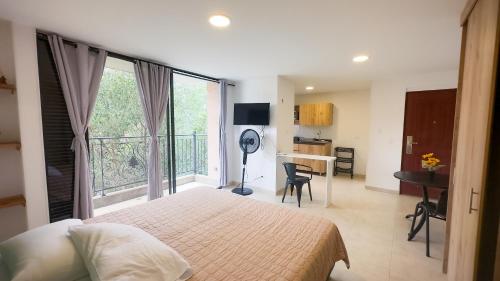 a bedroom with a bed and a balcony with a desk at Edificio Fenicia Lofts Laureles in Medellín