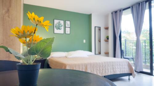 a bedroom with a bed and a table with yellow flowers at Edificio Fenicia Lofts Laureles in Medellín