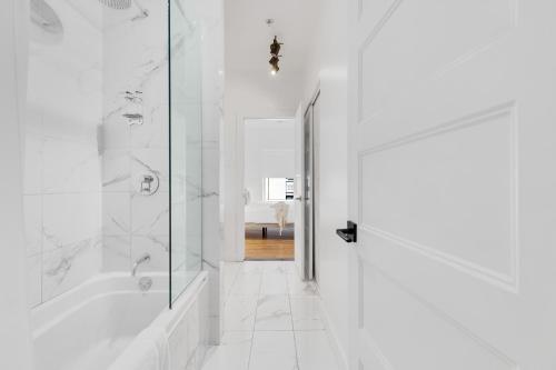 a white bathroom with a shower and a tub at The SFX Old Port in Montréal