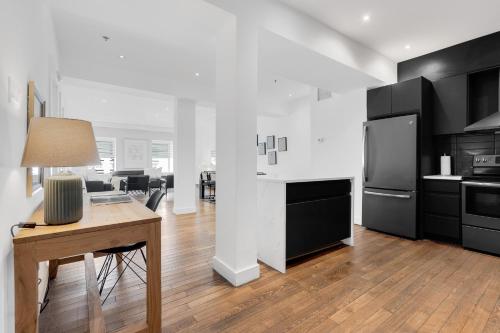 a kitchen with black cabinets and a table and a refrigerator at The SFX Old Port in Montréal