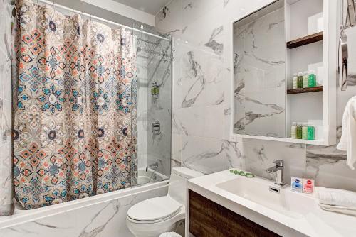a bathroom with a shower curtain and a toilet and a sink at The SFX Old Port in Montréal