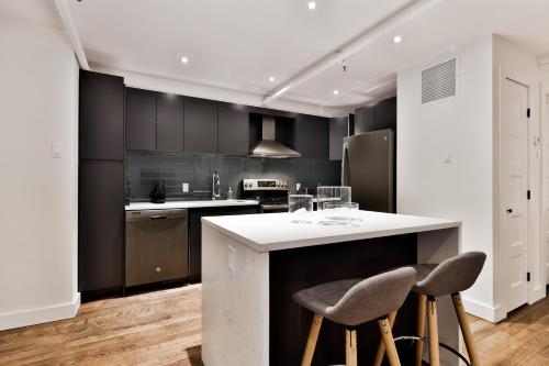 a kitchen with black cabinets and a white counter top at The SFX Old Port in Montréal