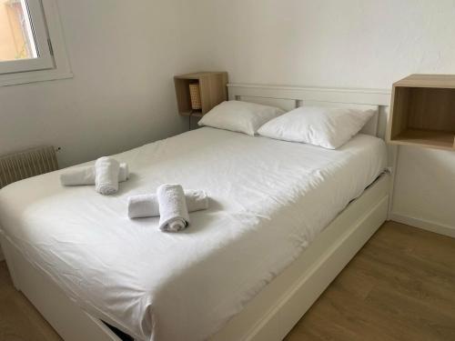 un lit blanc avec des serviettes dessus dans l'établissement Le Colvert, appartement face mer, au Crotoy