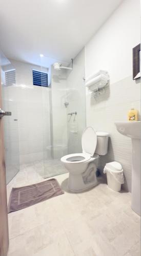 a white bathroom with a toilet and a shower at Edificio Fenicia Lofts Laureles in Medellín
