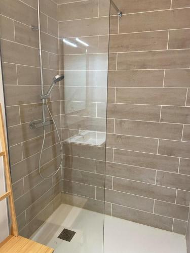 une douche avec une porte vitrée dans une salle de bain dans l'établissement Le Colvert, appartement face mer, au Crotoy