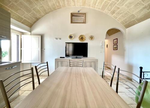 a large dining room with a table and a flat screen tv at Trullo vista mare con idromassaggio in Marina San Gregorio