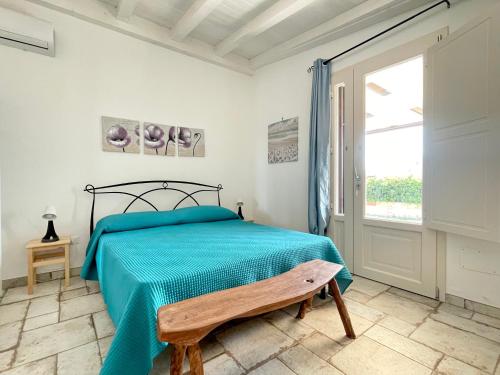 a bedroom with a bed with a blue blanket and a window at Trullo vista mare con idromassaggio in Marina San Gregorio