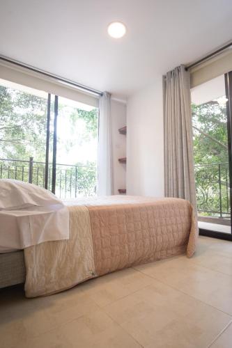 a bedroom with a bed and a large window at Edificio Fenicia Lofts Laureles in Medellín