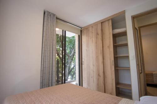 a bedroom with a bed and a large window at Edificio Fenicia Lofts Laureles in Medellín