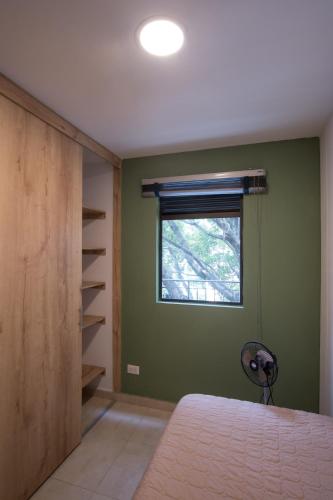 a bedroom with a green wall and a window at Edificio Fenicia Lofts Laureles in Medellín