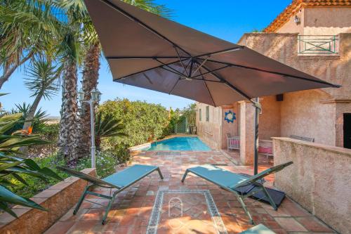 un patio avec deux chaises et un parasol à côté d'une piscine dans l'établissement Villa 