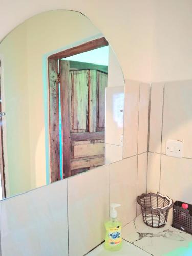 a bathroom with a mirror with a door in it at Zai Homes Watamu in Watamu