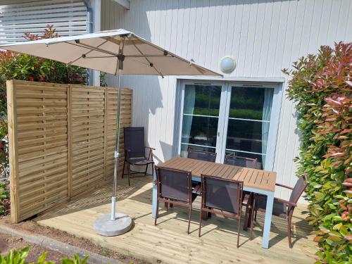 un parasol sur une terrasse avec une table et des chaises dans l'établissement Maison 3 piscines - Résidence 3 étoiles, à Pornichet