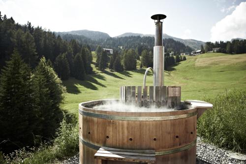 a wooden tub with a fountain in a field at Maiensässhotel Guarda Val in Lenzerheide