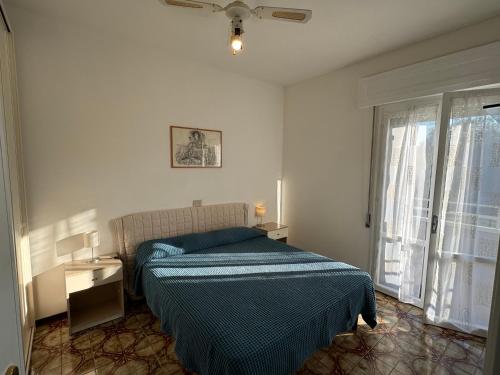 a bedroom with a bed with a blue blanket and a window at Appartamento Gina lido di savio in Lido di Savio