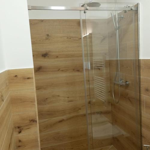 a shower with a glass door and wooden floor at La finestra sugli ulivi in Pezze di Greco