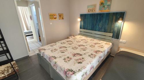 a small bedroom with a bed with a floral bedspread at Garden House Katerina in Leptokaria
