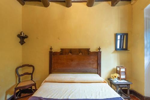 a bedroom with a bed with a wooden headboard and a chair at Can Marc in Dosríus