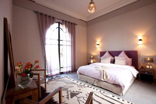 a bedroom with a large bed and a window at Villa de luxe avec piscine sur le golf d'amelkis in Marrakech