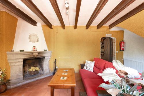 a living room with a red couch and a fireplace at Can Marc in Dosríus